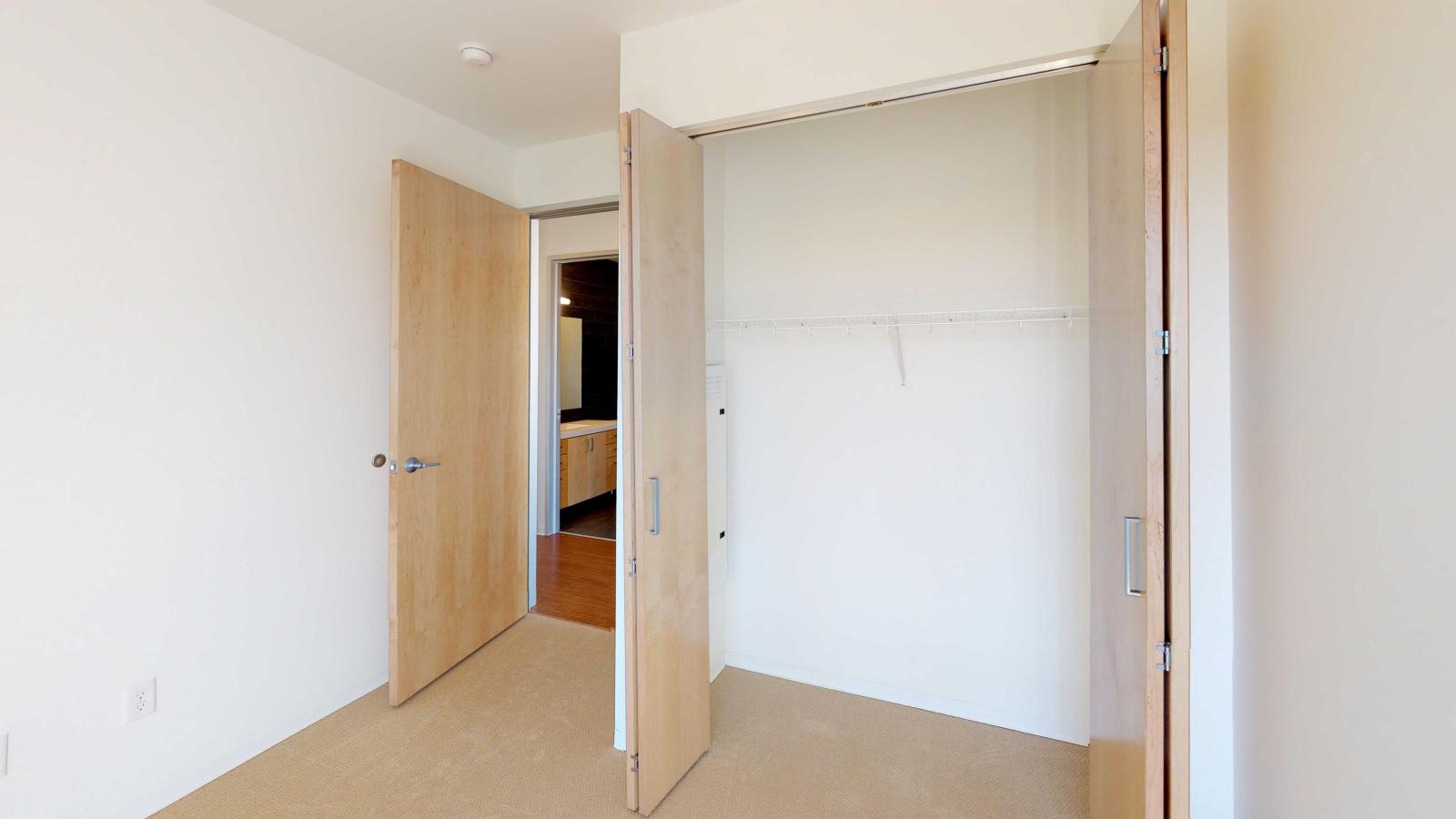Guest bedroom in a two bedroom apartment with standard closet and soft neutral tones at SEVEN27